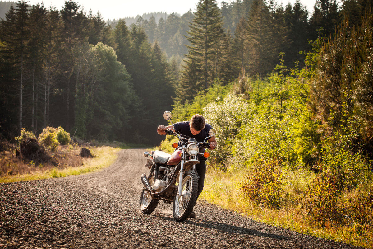 バイクを押して歩くライダー